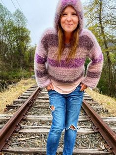 a woman standing on train tracks with her hands in her pockets