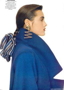 a woman wearing a blue coat with a bow in her hair and gold earring