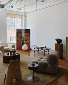 a living room filled with lots of furniture and art work on the wall behind it