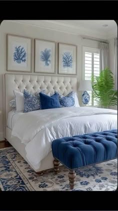 a bedroom with blue and white decor on the walls, an upholstered bed, and two framed pictures above it