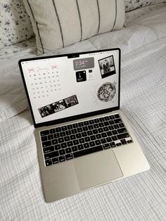 an open laptop computer sitting on top of a bed next to pillows and throw pillows