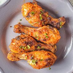 three pieces of chicken on a plate with parsley sprinkled on the wings