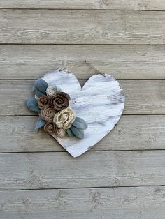 a heart shaped wooden decoration with flowers on it's side against a wood plank wall