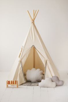 a teepee tent with pillows on the floor next to it