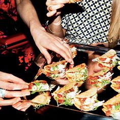 several people reaching for sandwiches on a tray