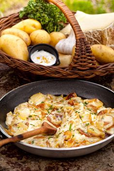 a pan filled with food sitting on top of a counter next to potatoes and other vegetables