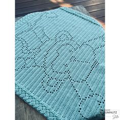 a blue crocheted blanket sitting on top of a wooden floor next to a table