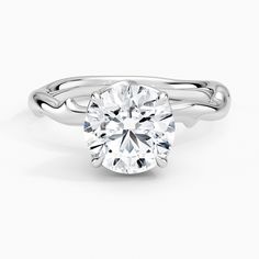 a white gold engagement ring with a round cut diamond in the center and twisted band