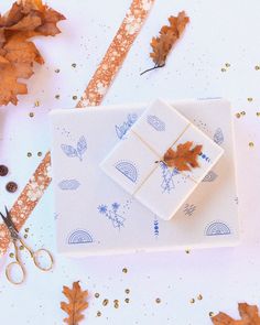 autumn leaves, scissors and paper on a white surface with gold glitters around them