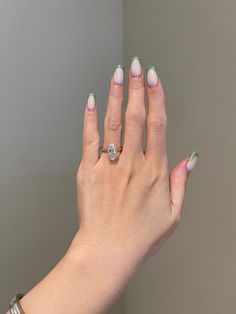 a woman's hand with green and white manicures holding a diamond ring