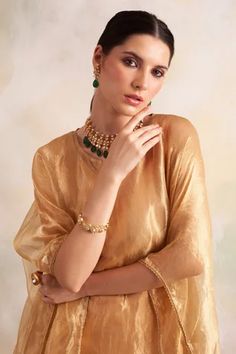 Gold tissue kaftan style kurta with lace trims and tassel hem. Comes with soft modal gold pant.
Component: 2
Pattern: Solid
Neckline: V-Neck
Sleeve Type: Batwing
Fabric: Kurta: Tissue, Pant: Soft Modal
Color: Gold
Other Details: 
Tassel hem
Lace trims
Side slits
Note: Inner worn by the model is not for sale
Occasion: Mehendi and Haldi - Aza Fashions Elegant Festive Sets With Back Tassel Tie-up, Designer Elegant Sharara With Tassels, Elegant Designer Wear Sharara With Tassels, Elegant Eid Sets With Tassels, Elegant Sets With Tassels For Diwali, Eid Sharara With Latkans, Kaftan Kurta, Gold Pants, Kaftan Style