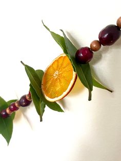 an orange is cut in half and placed on top of some leaves with other fruits around it