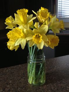 a glass jar filled with yellow flowers on top of a counter