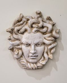 a sculpture of a man's head with hair on it is hanging on the wall