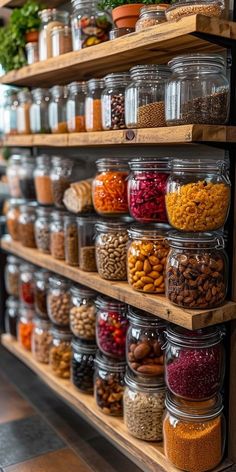 the shelves are filled with many different kinds of spices and nuts in glass jars on wooden racks