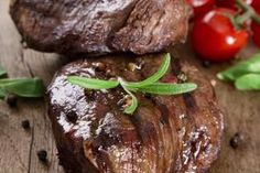 steaks and tomatoes on a wooden cutting board