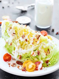 lettuce and tomato salad on a white plate with a glass of milk in the background