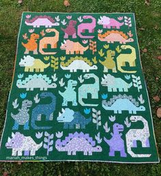 a green quilt with dinosaurs on it and numbers in the middle, sitting on grass