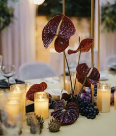 a table topped with candles and flowers next to other place settings for a dinner party