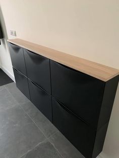 an empty room with a black cabinet and grey flooring on the wall, next to a gray tile floor