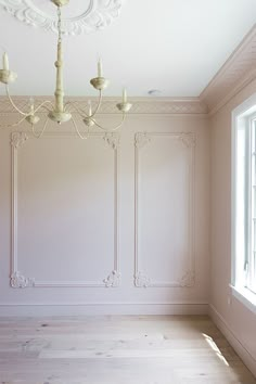 an empty room with chandelier and white walls