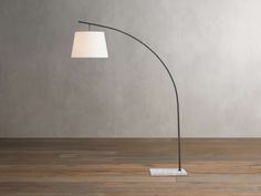 a floor lamp with a white shade on it and a wooden floor next to it