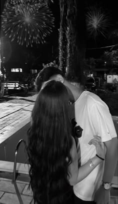 a man and woman kissing in front of fireworks