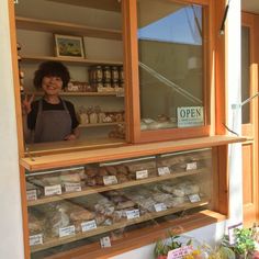 a woman standing in front of a bakery window