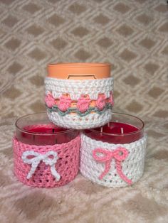 three crocheted candles are sitting next to each other on a bed with a pink candle holder