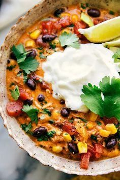 a white bowl filled with chili, beans and sour cream on top of a table