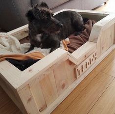 a dog laying in a wooden crate on the floor