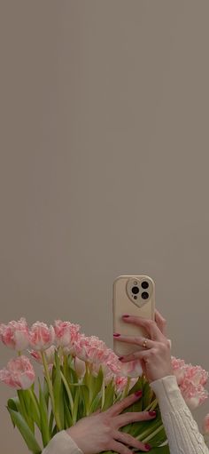 a woman taking a selfie with her cell phone in front of pink carnations