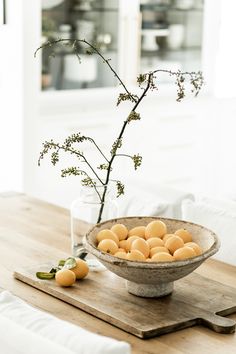 a bowl filled with eggs sitting on top of a wooden table next to a vase