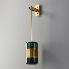 a green and gold light hanging from a wall next to a gray wall with a white background