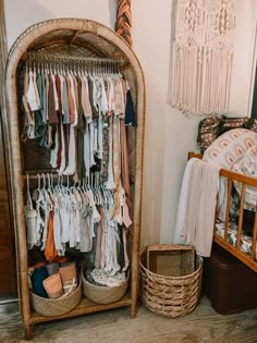 a wicker closet filled with baby clothes next to a crib