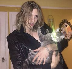 a man holding a cat in his arms with a green light shining on it's face