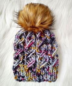 a multicolored knitted hat with a pom - pom on top