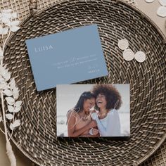 two cards sitting on top of a wicker plate next to some coins and flowers