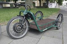 a green motorcycle is parked on the side of the road with a trailer attached to it