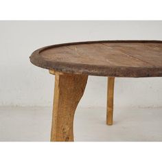 an old wooden table with two legs and a round wood plate on the top that has been turned into a coffee table