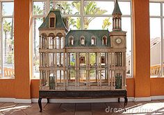 a doll house sitting on top of a wooden table in front of a large window