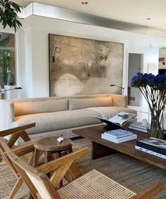 a living room filled with furniture and a large painting on the wall above it's coffee table