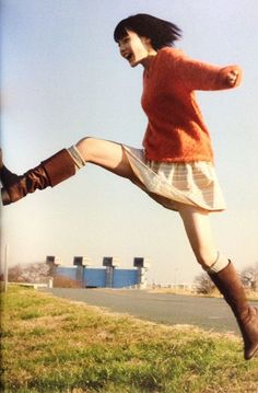 a woman is jumping in the air with her legs spread out to catch a frisbee