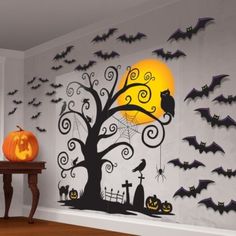 a room decorated for halloween with pumpkins, bats and a tree on the wall