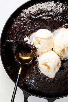 two scoops of ice cream are in a skillet with chocolate sauce and vanilla