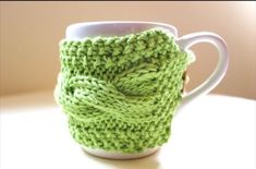 a green knitted cup cozys up on a table