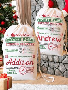 two bags sitting next to a christmas tree with presents in front of it and the words north pole express delivery printed on them