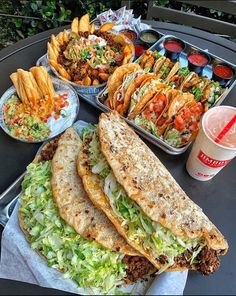 a table topped with trays of food and plates filled with different types of foods