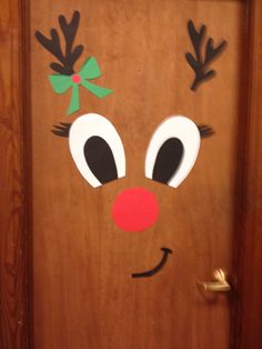 a door decorated to look like a reindeer's head with green bow and nose