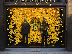 two mannequins are standing in front of a window with yellow butterflies on it